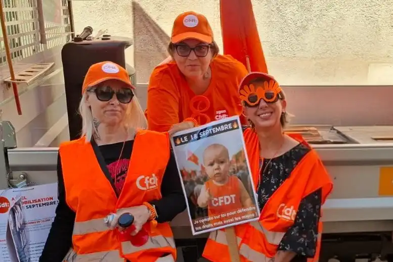 Photo de trois militantes CFDT en gilet orange